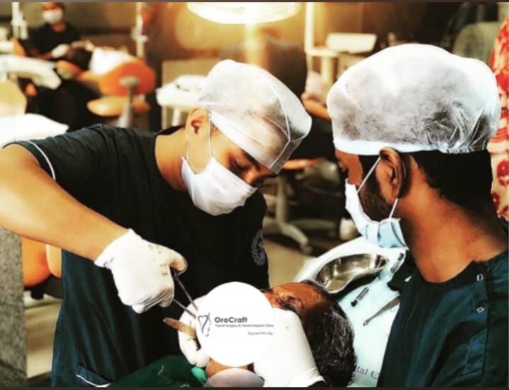 Two surgeons in protective gear perform a dental procedure on a patient at OroCraft clinic.